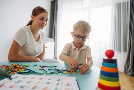 Educational game with toys. Speech therapist is with young boy indoors.